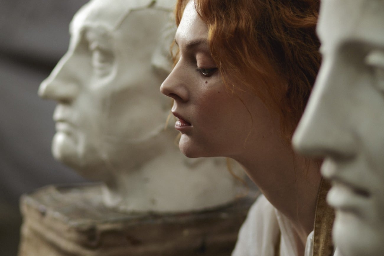 woman sitting between statues