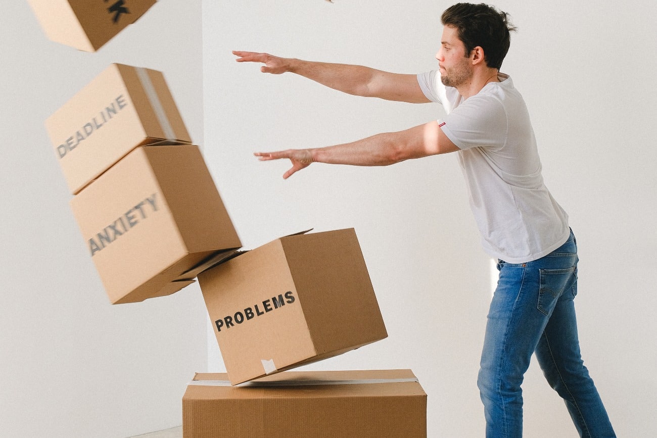 man pushing over boxes labeled with anxiety and problems