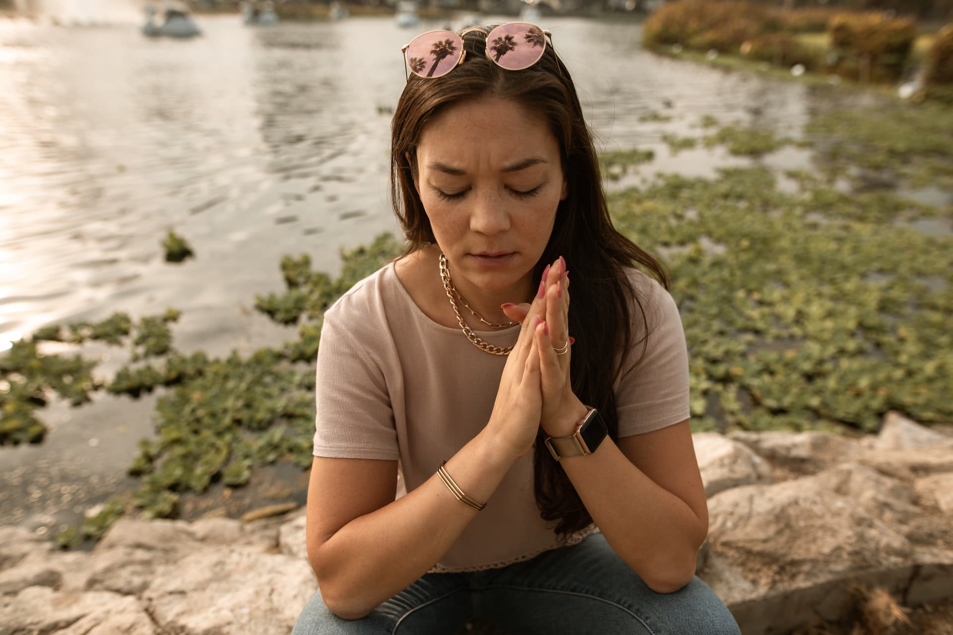 stressed woman with eyes closed on lake shore